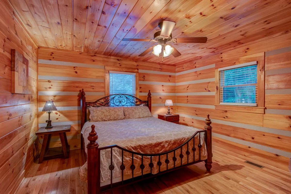 A warmly lit bedroom featuring a wooden ceiling, an ornate bed with a plush headboard, and nightstands with lamps. The room exudes a sense of calm and comfort, ideal for relaxation after a day of adventure.