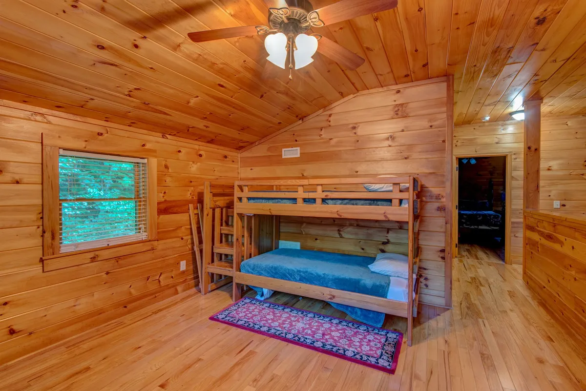 A cheerful loft space with a sturdy wooden bunk bed, soft rug, and a window that allows natural light to fill the room. The playful design makes it ideal for children or young guests, while the additional floor space could easily accommodate a desk or play area.