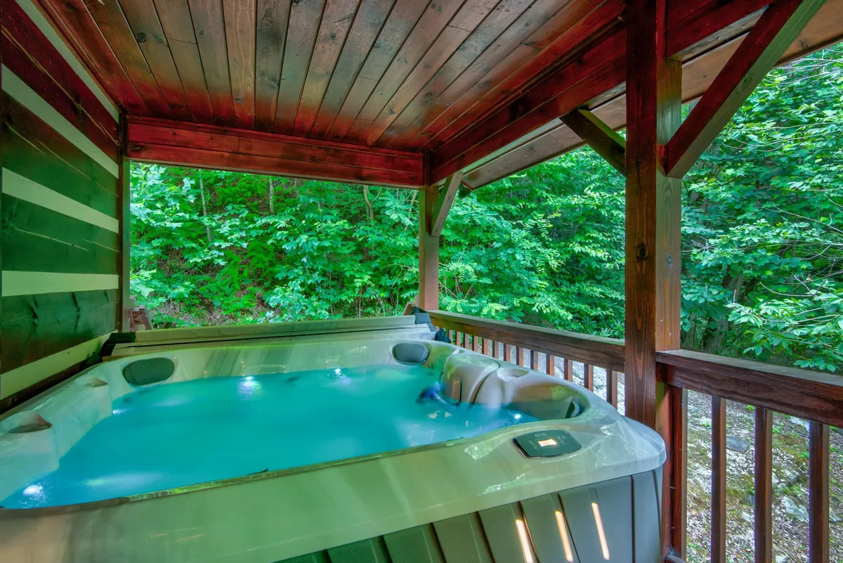 An inviting hot tub area indoors, framed by natural wooden beams and windows that showcase the surrounding greenery. The space suggests relaxation after an active day outdoors, and the visual connection to nature blurs the line between inside comfort and outside adventure.