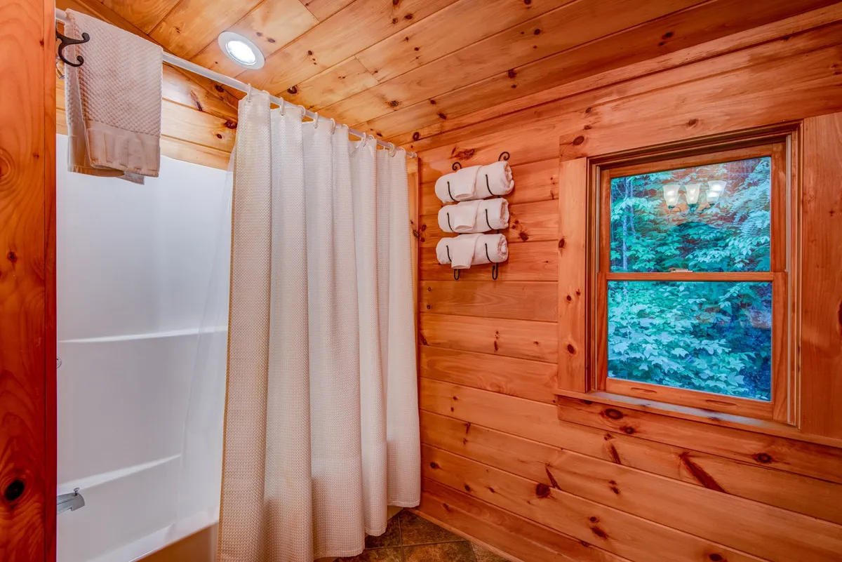 A modern bathroom featuring a sleek shower area, a window with a scenic view, and a towel rack. The calming, serene mood suggests a luxurious space for unwinding and personal care.